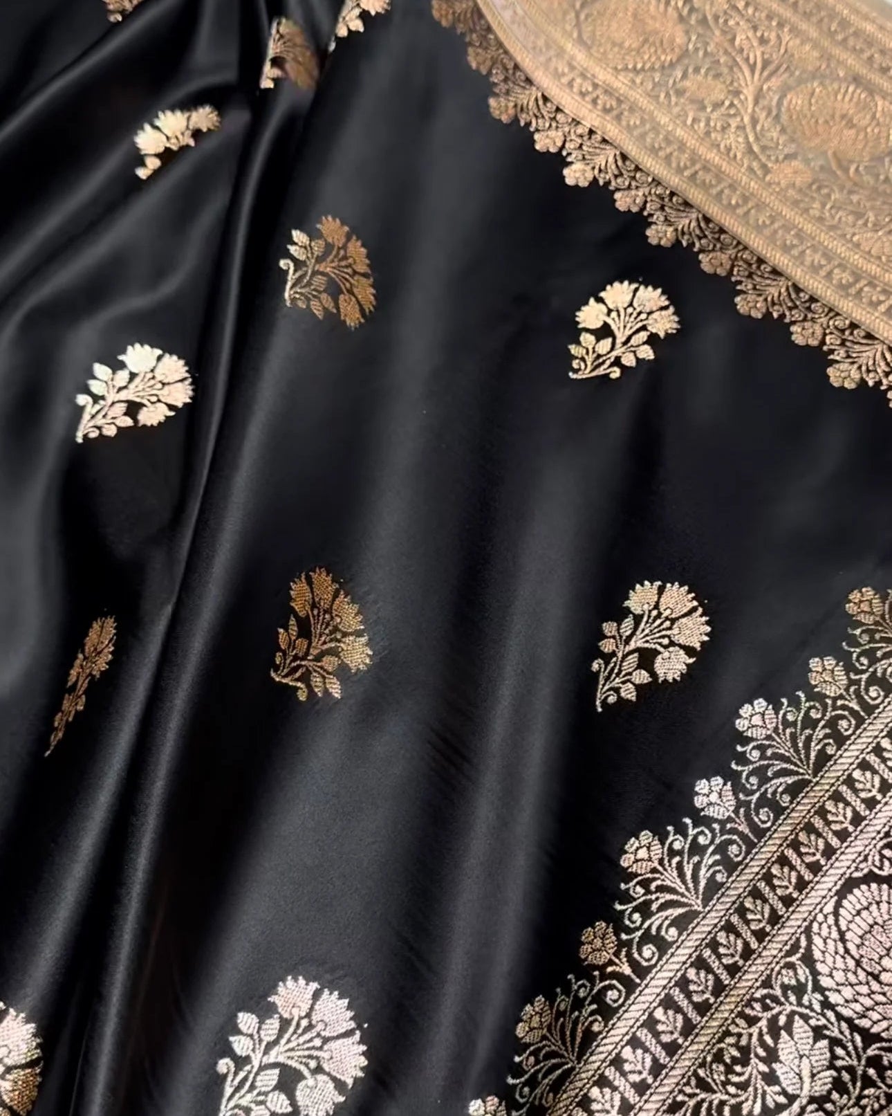 Black silk Banarasi saree with intricate gold and silver floral motifs and a detailed gold border.