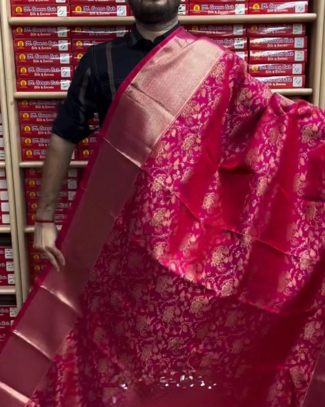 Person wearing a pink saree with a pattern in a store setting
