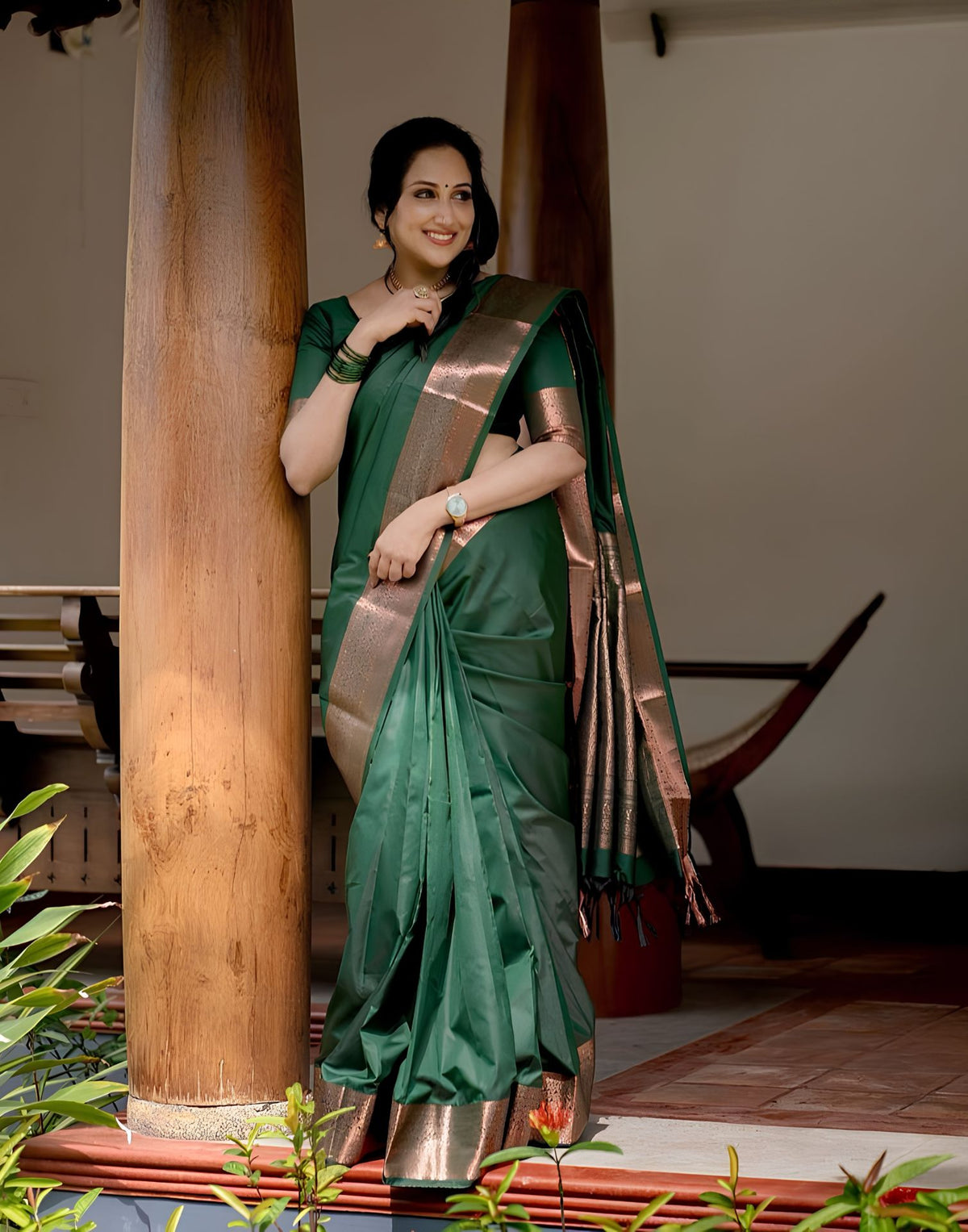 A folded metallic gold and silver patterned silk scarf or sash is displayed inside a white box next to a light green shirt, with a hand holding the top edge of the fabric.